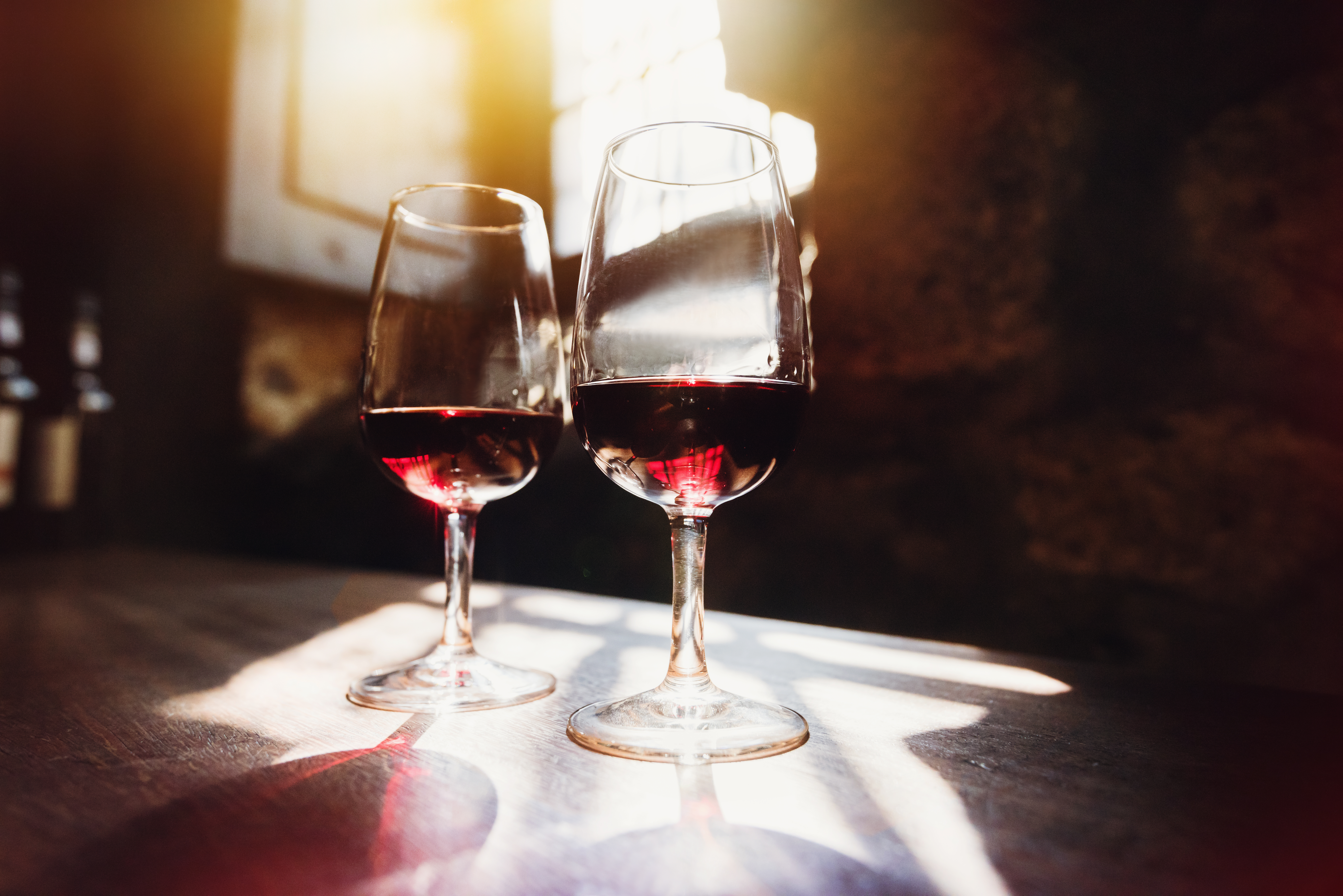 To elegante vinglas med rød vin i varmt sollys - perfekt til romantisk ferie