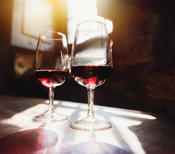 To elegante vinglas med rød vin i varmt sollys - perfekt til romantisk ferie