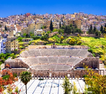 Historisk romersk amfiteater med panoramaudsigt over Ammans bykerne i Jordan, der viser kontrasten mellem antikke ruiner og moderne bylandskab