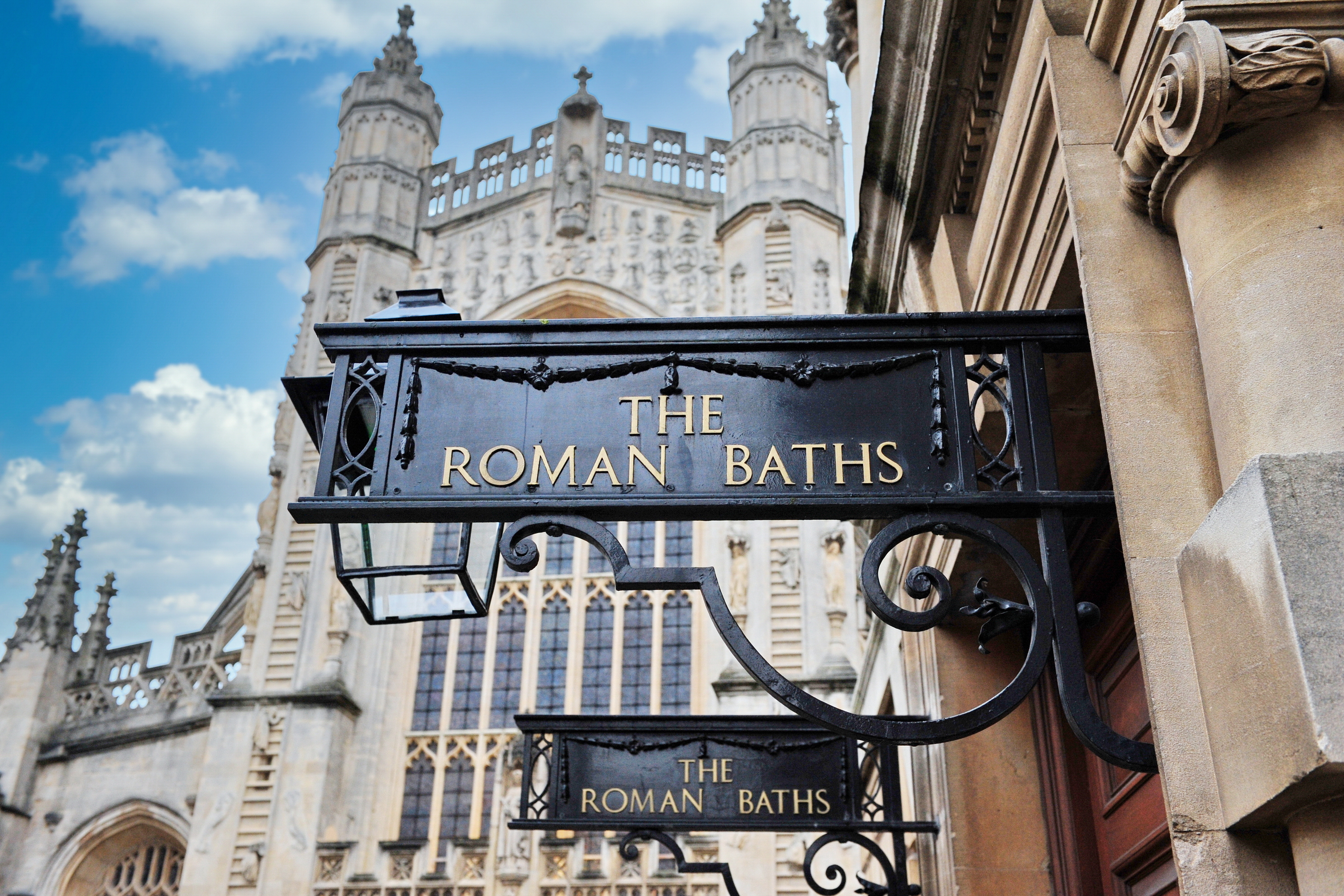 Romerske Bade indgang skilt med Bath Abbey arkitektur i Bath England