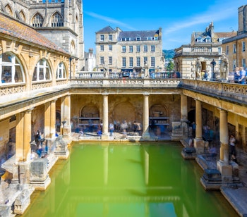 De historiske romerske bade i Bath med damp fra termiske kilder omgivet af antikke søjler og arkitektur