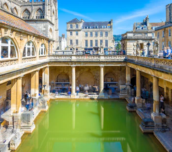 De historiske romerske bade i Bath med damp fra termiske kilder omgivet af antikke søjler og arkitektur