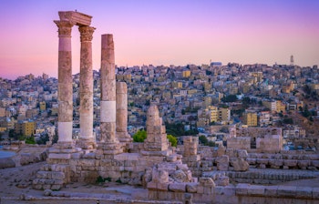 Historiske romerske ruiner i Amman Citadel ved solnedgang med smuk udsigt over Jordans hovedstad og byens gamle bydel
