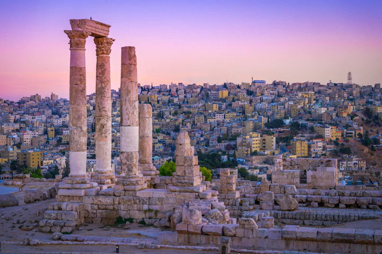Historiske romerske ruiner i Amman Citadel ved solnedgang med smuk udsigt over Jordans hovedstad og byens gamle bydel