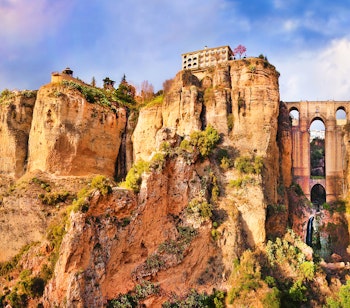 Betagende panoramaudsigt over Ronda ved solnedgang, en af Andalusiens berømte hvide landsbyer, dramatisk placeret på kanten af El Tajo-kløften med den ikoniske Puente Nuevo-bro