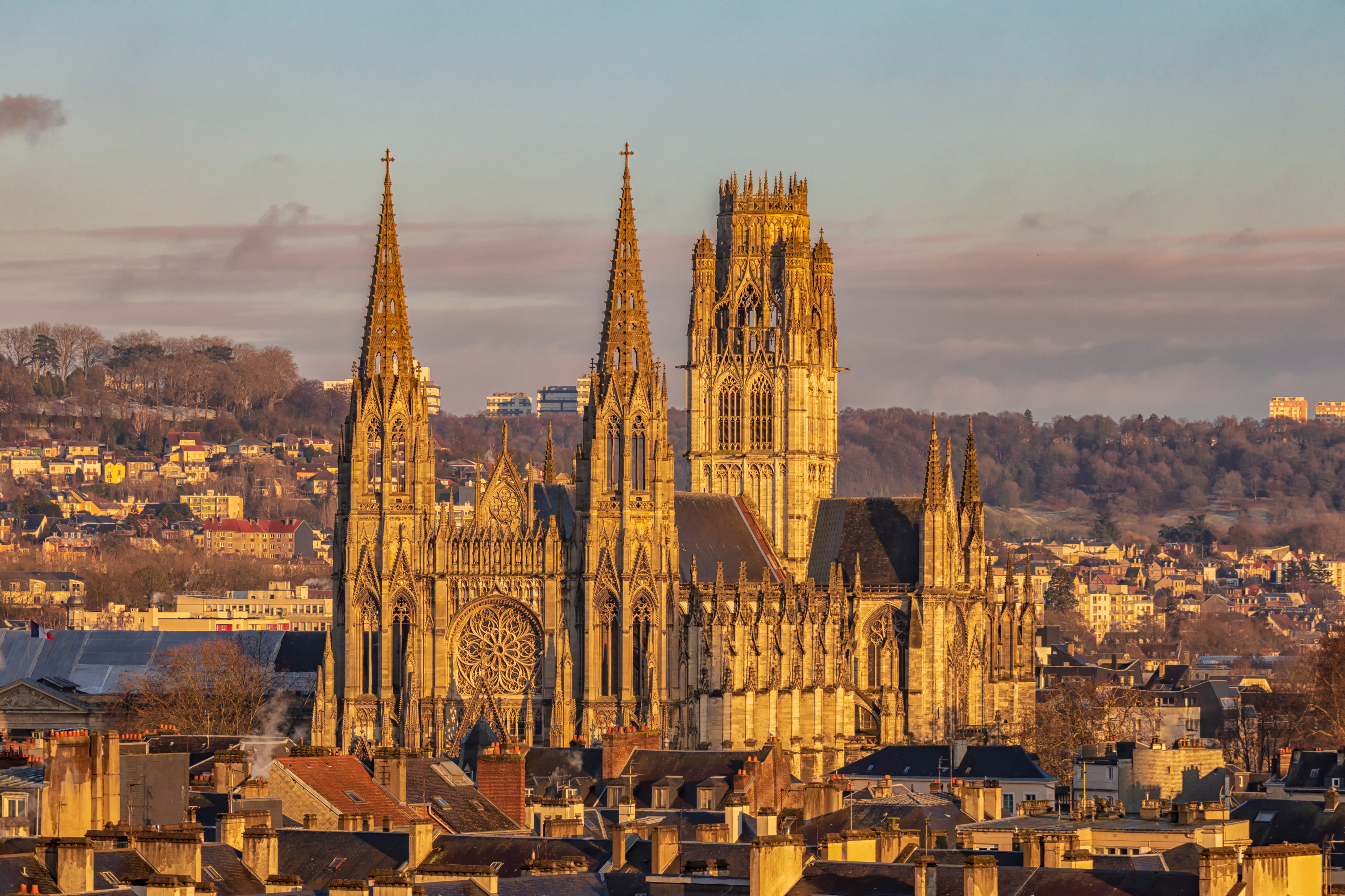Majestætisk gotisk katedral i Rouen badet i gyldent solnedgangslys med karakteristiske spir og rosette-vindue over byens historiske centrum i Normandiet