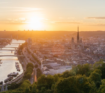 Panoramaudsigt over Rouen i Normandiet med den gotiske katedral og Seine-floden badet i gyldent solnedgangslys