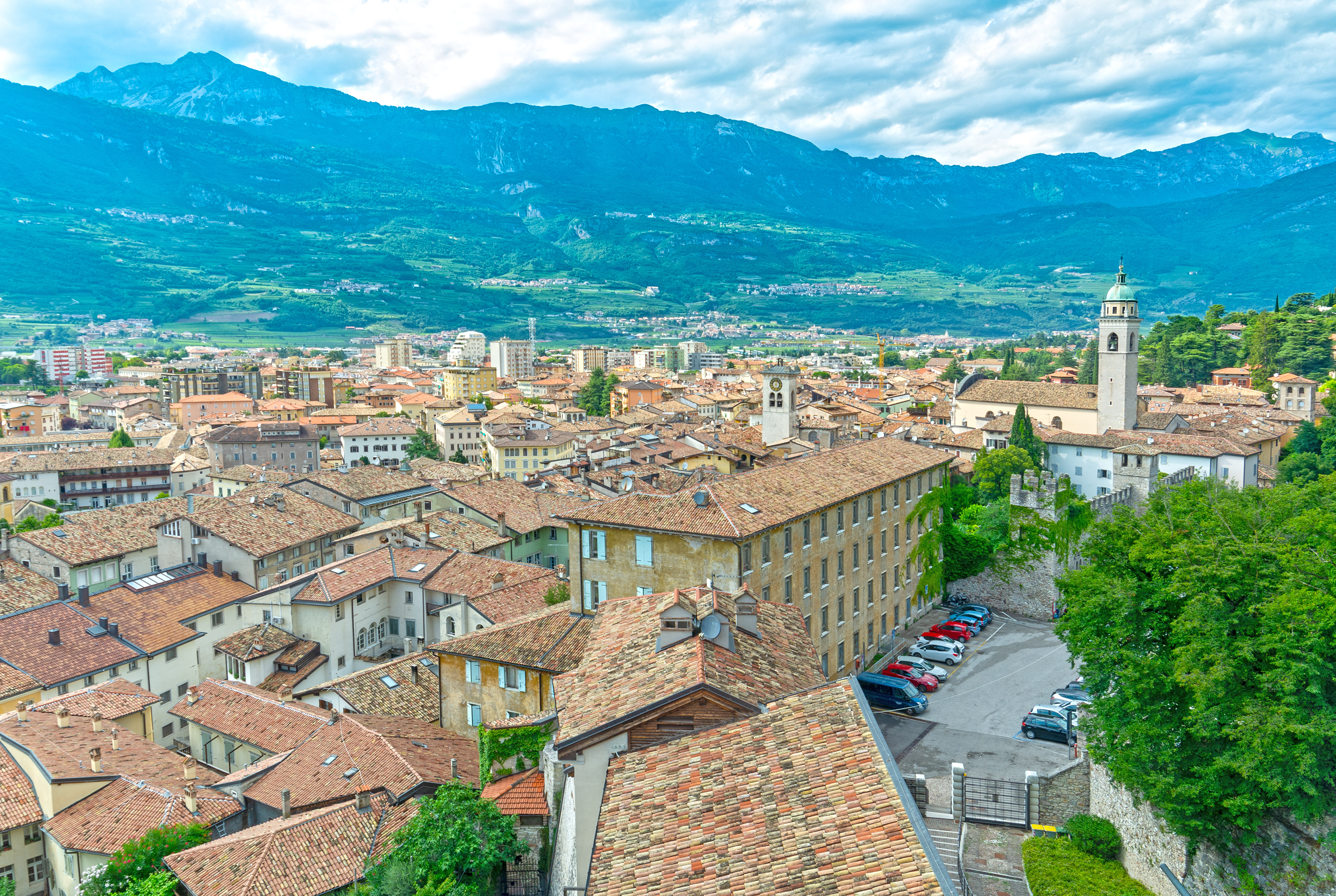 Luftudsigt over Rovereto i Trentino, Italien, med røde tagsten, klokketårn og de italienske Alper i baggrunden