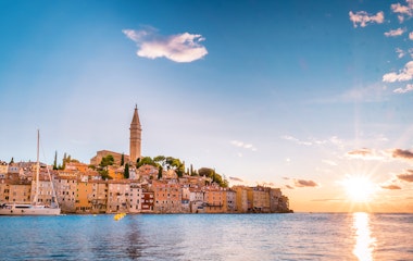 Malerisk solnedgang over den gamle bydel i Rovinj, Istrien med det ikoniske kirketårn og farverige bygninger ved Adriaterhavets kyst
