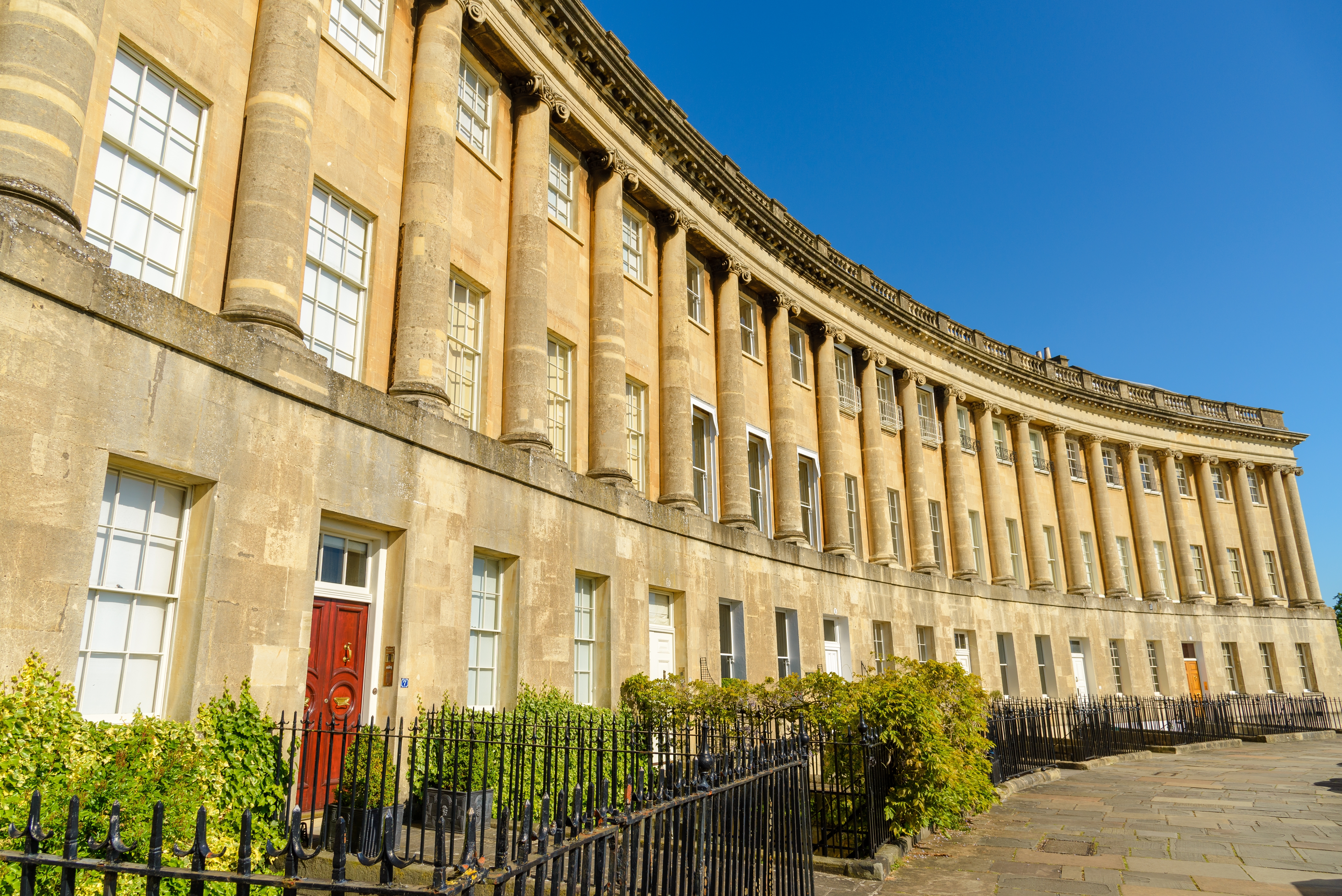 Royal Crescent i Bath, England – smuk georgisk terrassehusarkitektur med gyldne kalkstenscolonner under blå himmel
