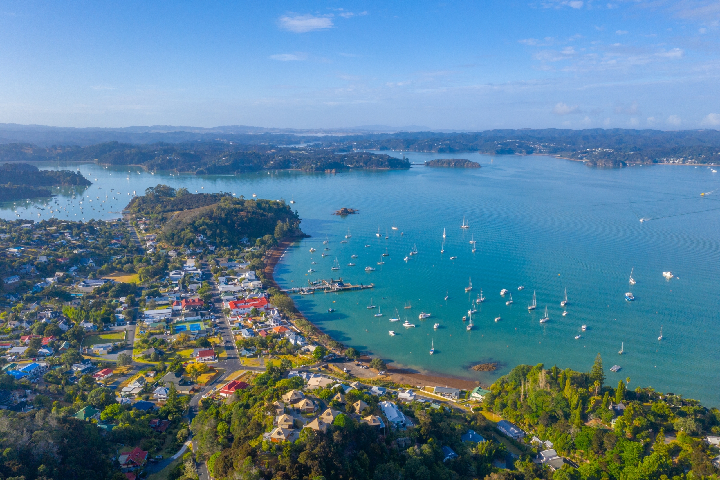 Luftfoto af Russell Bay på New Zealand med sejlbåde og kystby