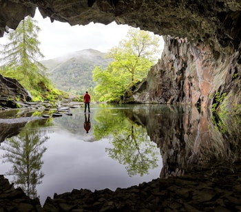Betagende udsigt over Rydal Cave i Lake District, England, med krystalklart vand og frodige grønne omgivelser
