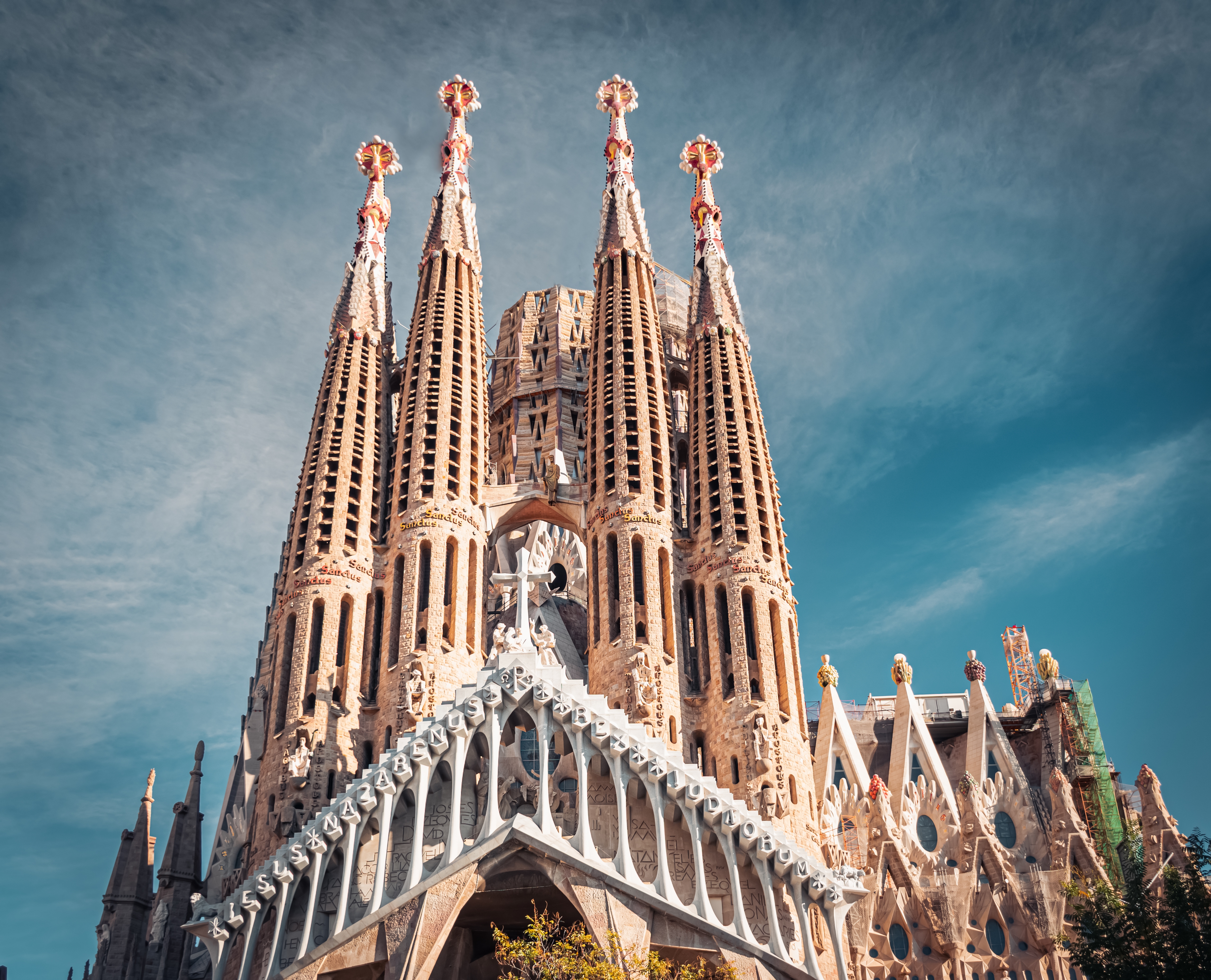 Den ikoniske Sagrada Familia basilika i Barcelona, Spanien, med Antoni Gaudís imponerende spir og detaljerede stenfacade mod en blå himmel