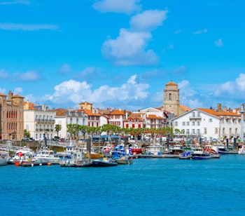 Idyllisk udsigt over den historiske fiskerby Saint Jean de Luz med farverige bygninger og bådhavn i det franske Baskerland