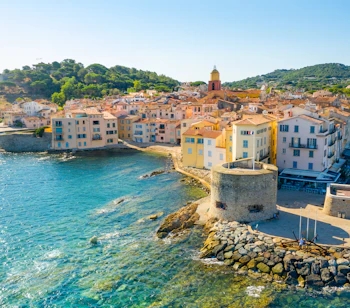 Betagende udsigt over Saint-Tropez havn med luksusyachter, farverige bygninger og det azurblå Middelhav på den franske riviera
