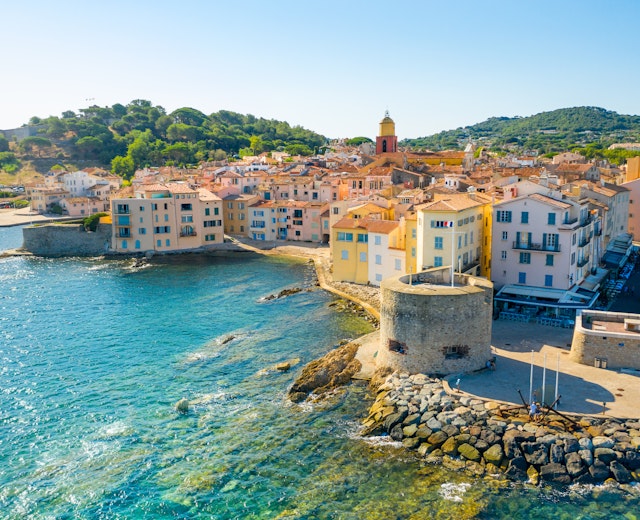 Betagende udsigt over Saint-Tropez havn med luksusyachter, farverige bygninger og det azurblå Middelhav på den franske riviera