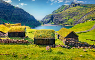 Idyllisk sommerlandskab i Saksun landsby med traditionelle græstørvhuse omgivet af grønne bjerge på Streymoy, Færøerne