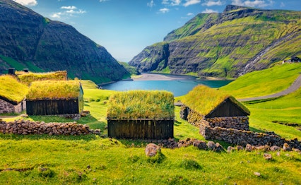 Idyllisk sommerlandskab i Saksun landsby med traditionelle græstørvhuse omgivet af grønne bjerge på Streymoy, Færøerne