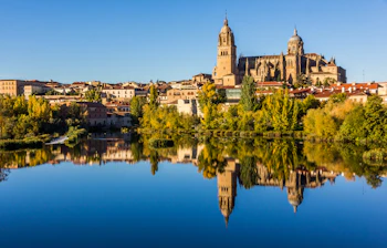 Salamancas smukke katedral spejler sig i Tormes-floden med historisk spansk bybillede
