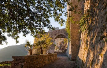 Middelalderlig stenport på Salerno borg med palmer og bjerglandskab på Amalfikysten Italien