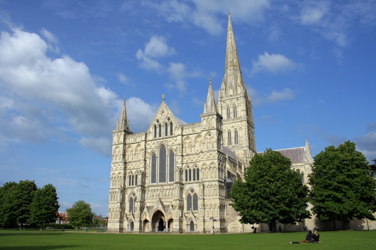 Den historiske Salisbury Katedral med gotisk spir og middelalderarkitektur under blå himmel i England