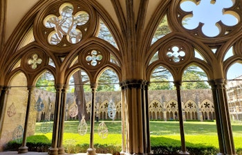Detaljeret billede af de elegante gotiske buer i den middelalderlige klostergang i Salisbury Katedral, der viser den imponerende stenarbejde og arkitektoniske skønhed i dette historiske engelske landemærke