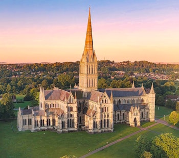 Betagende luftfoto af Salisbury Katedralen i England under den gyldne time med flot udsigt over den gotiske arkitektur og de grønne omgivelser