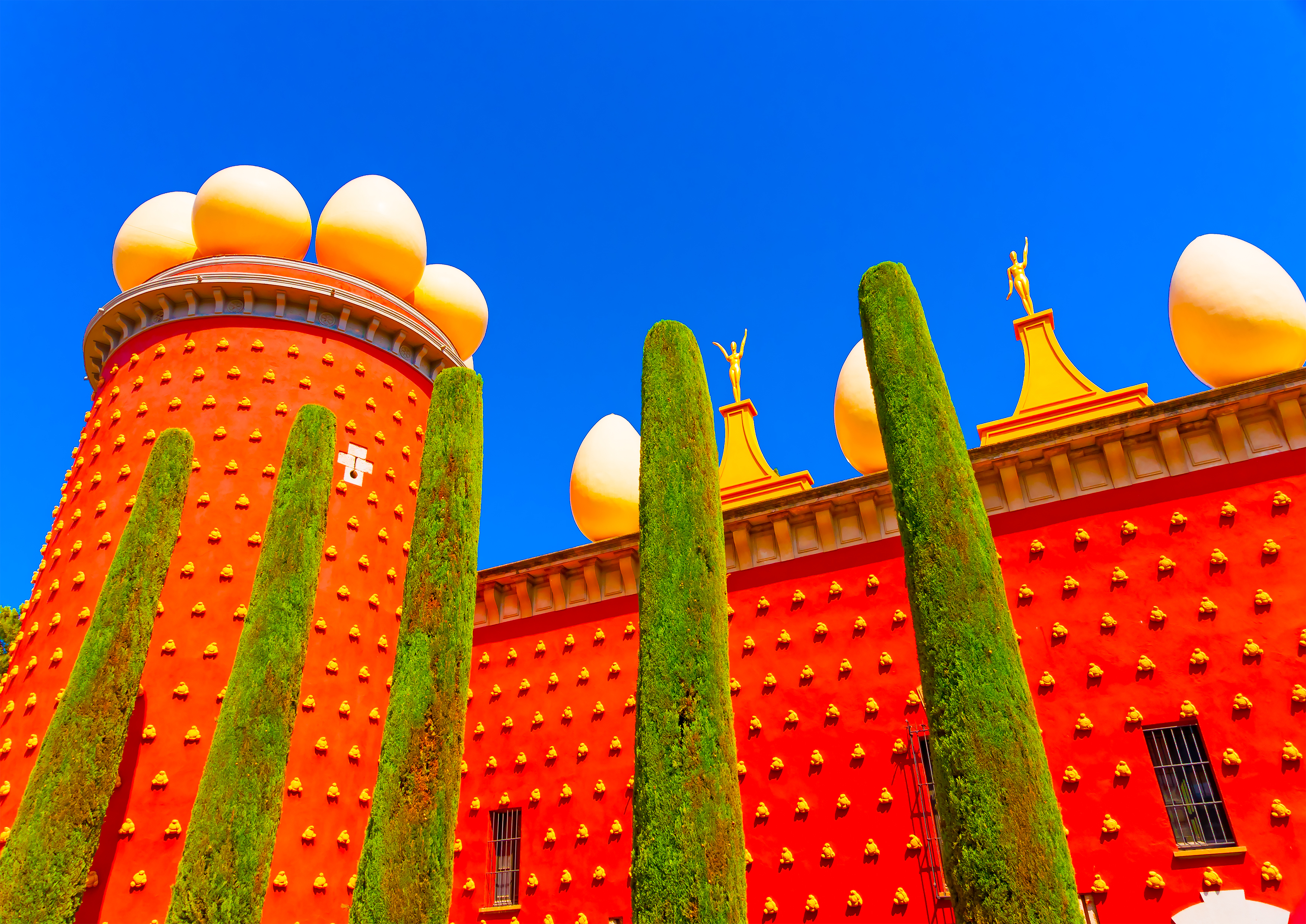 Salvador Dalí Museum-Teater i Figueres med ikonisk rød facade og surrealistiske ægformer under blå himmel
