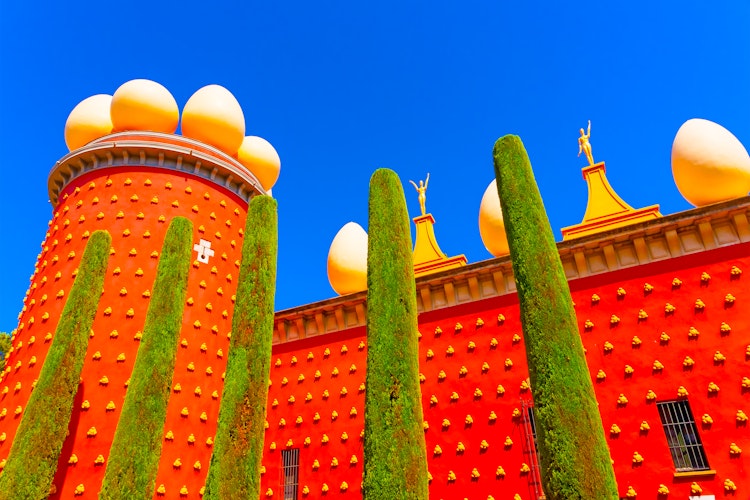 Salvador Dalí Museum-Teater i Figueres med ikonisk rød facade og surrealistiske ægformer under blå himmel
