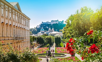 Betagende morgenudsigt over Salzburgs historiske bylandskab set fra Mirabellhaven med Hohensalzburg-fæstningen og bjerge i baggrunden