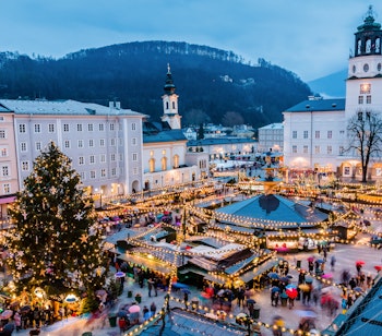 Traditionelt julemarked i den gamle bydel i Salzburg, Østrig med festlige dekorationer, træboder og oplyste historiske bygninger i skumringstimen