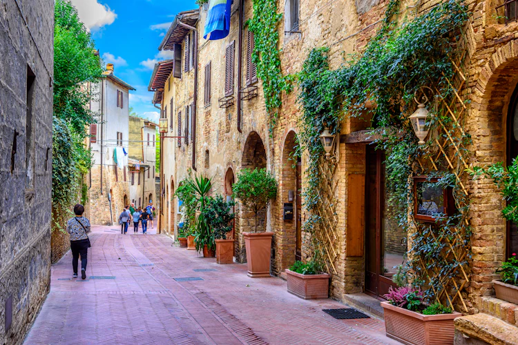 Charmerende middelalderlig gade i San Gimignano Toscana med stenbygninger og grønne planter