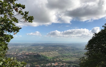 Betagende panoramaudsigt over San Marino fra bjergtop med grønne landskaber og historiske bygninger under blå himmel