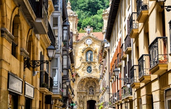 Charmerende gade i San Sebastians gamle bydel med traditionel baskisk arkitektur og kirke i baggrunden
