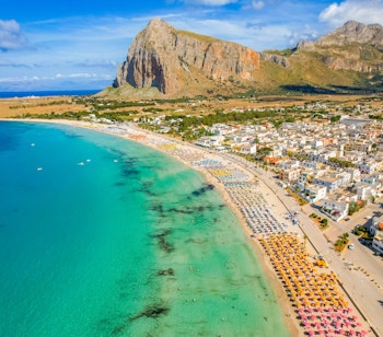 Idyllisk sandstrand ved San Vito lo Capo med Monte Monaco bjerget i baggrunden, krystalklart blåt vand og gyldent sand på Siciliens nordvestlige kyst