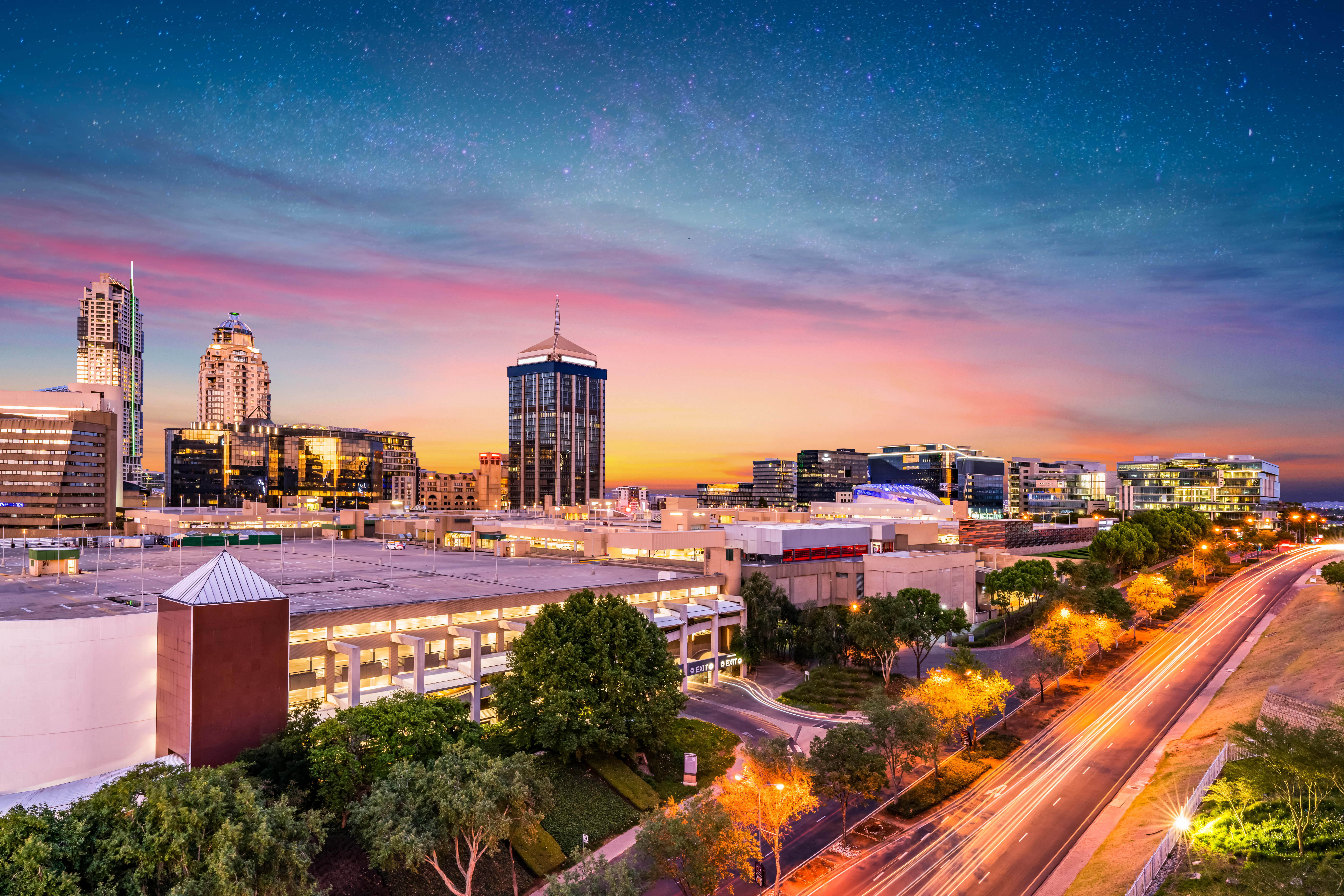 Imponerende aftenudsigt over Sandton City i Johannesburg med oplyste skyskrabere og stjernehimmel over Sydafrikas finansdistrikt