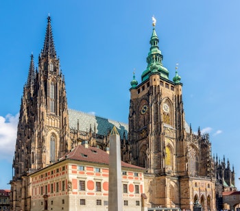 Sankt Vitus Domkirke på Prag Borg med gotiske tårne og grønt baroktårn mod blå himmel
