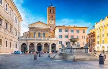 Den historiske Basilica di Santa Maria in Trastevere i Rom, verdens ældste kirke dedikeret til Jomfru Maria, med smuk mosaik-facade, klokketårn og den karakteristiske fontæne på den maleriske plads i Trastevere-kvarteret