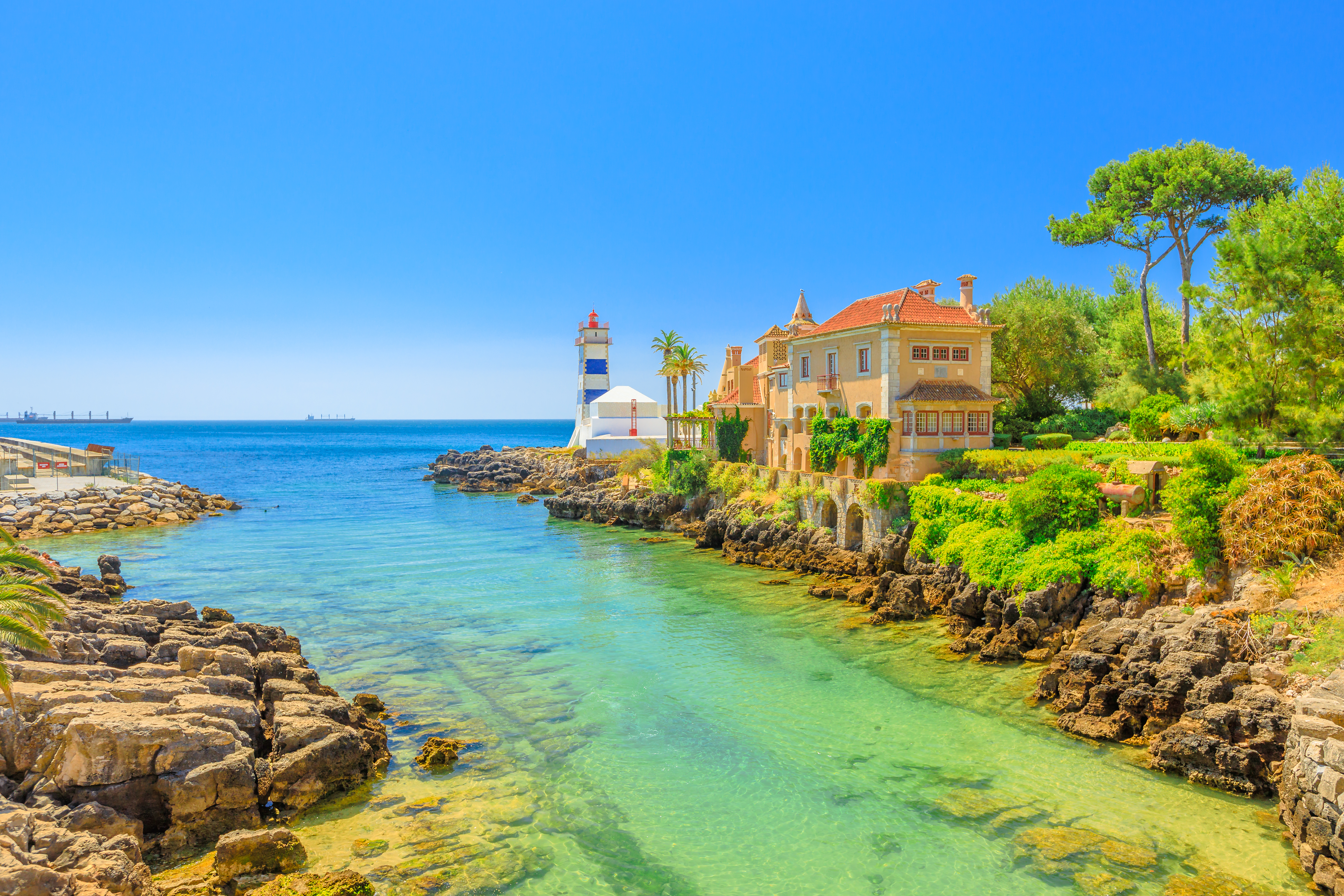 Det historiske Santa Marta fyrtårn og Casa de Santa Maria med udsigt over det turkisblå vand i Cascais, Portugal
