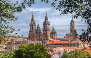 Den majestætiske Santiago de Compostela katedral i Spanien med sin imponerende middelalderlige facade, tårne og ornamenter under en blå himmel