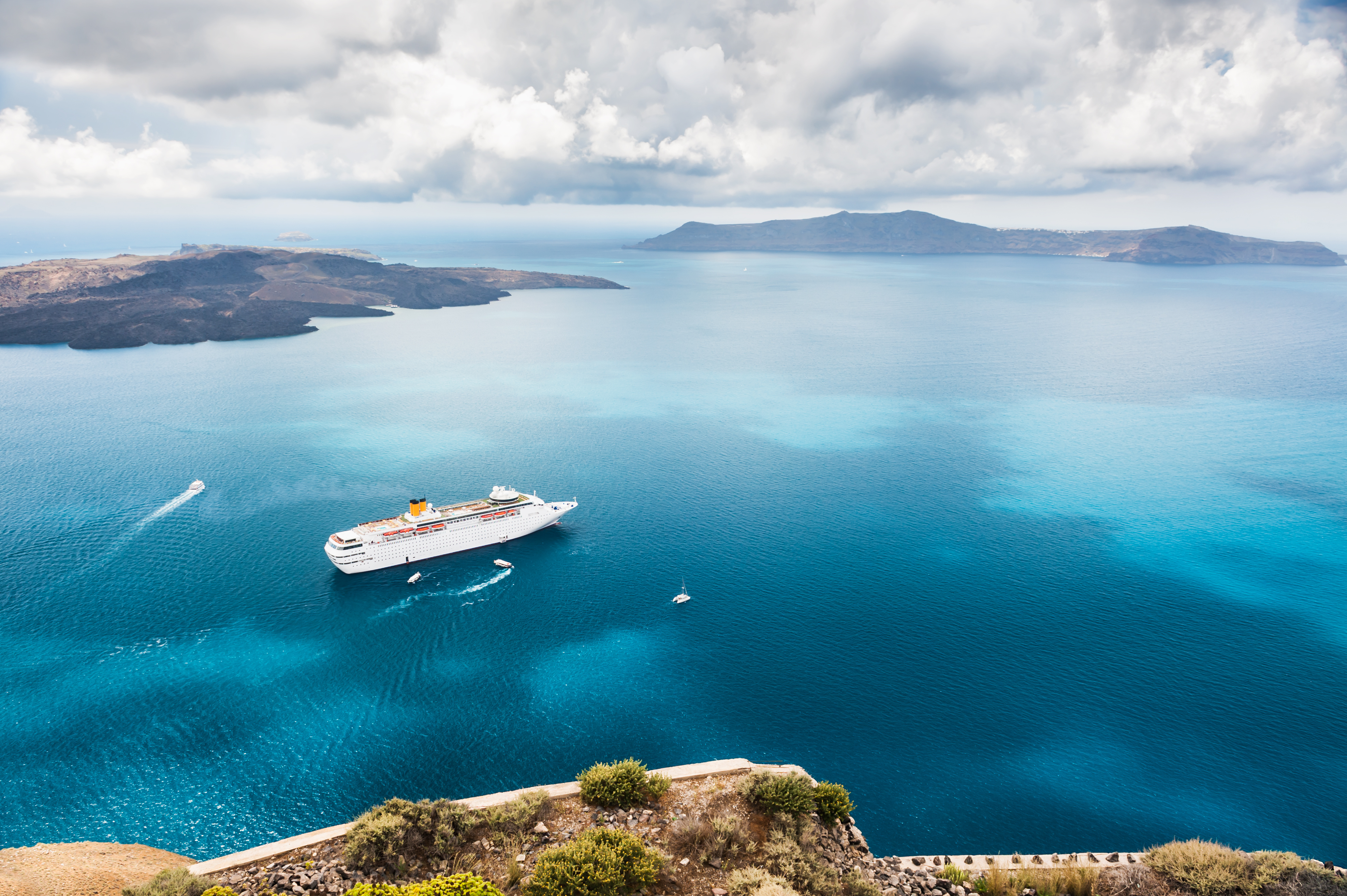 Krydstogtskib ved Santorini med det blå Ægæiske Hav og græske øer i baggrunden