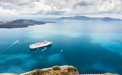 Krydstogtskib ved Santorini med det blå Ægæiske Hav og græske øer i baggrunden