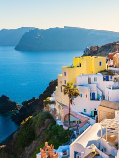 Smukke hvide bygninger i Oia på Santorini med solnedgang over det Ægæiske Hav - perfekt til en romantisk ferie i Grækenland