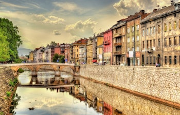 Panoramaudsigt over Sarajevos historiske centrum med Miljacka-floden og traditionel arkitektur under blå himmel