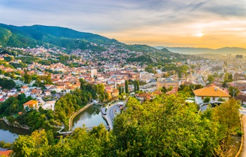 Betagende panoramaudsigt over Sarajevo i solnedgangslys set fra den Gule Fæstning (Žuta Tabija) i Vratnik-området, Bosnien-Hercegovina