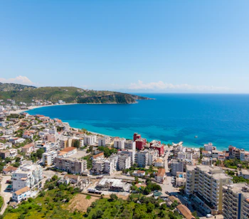 Luftfoto af Saranda i Albanien med turkisblåt hav og hvide bygninger langs den smukke Ioniske kyst
