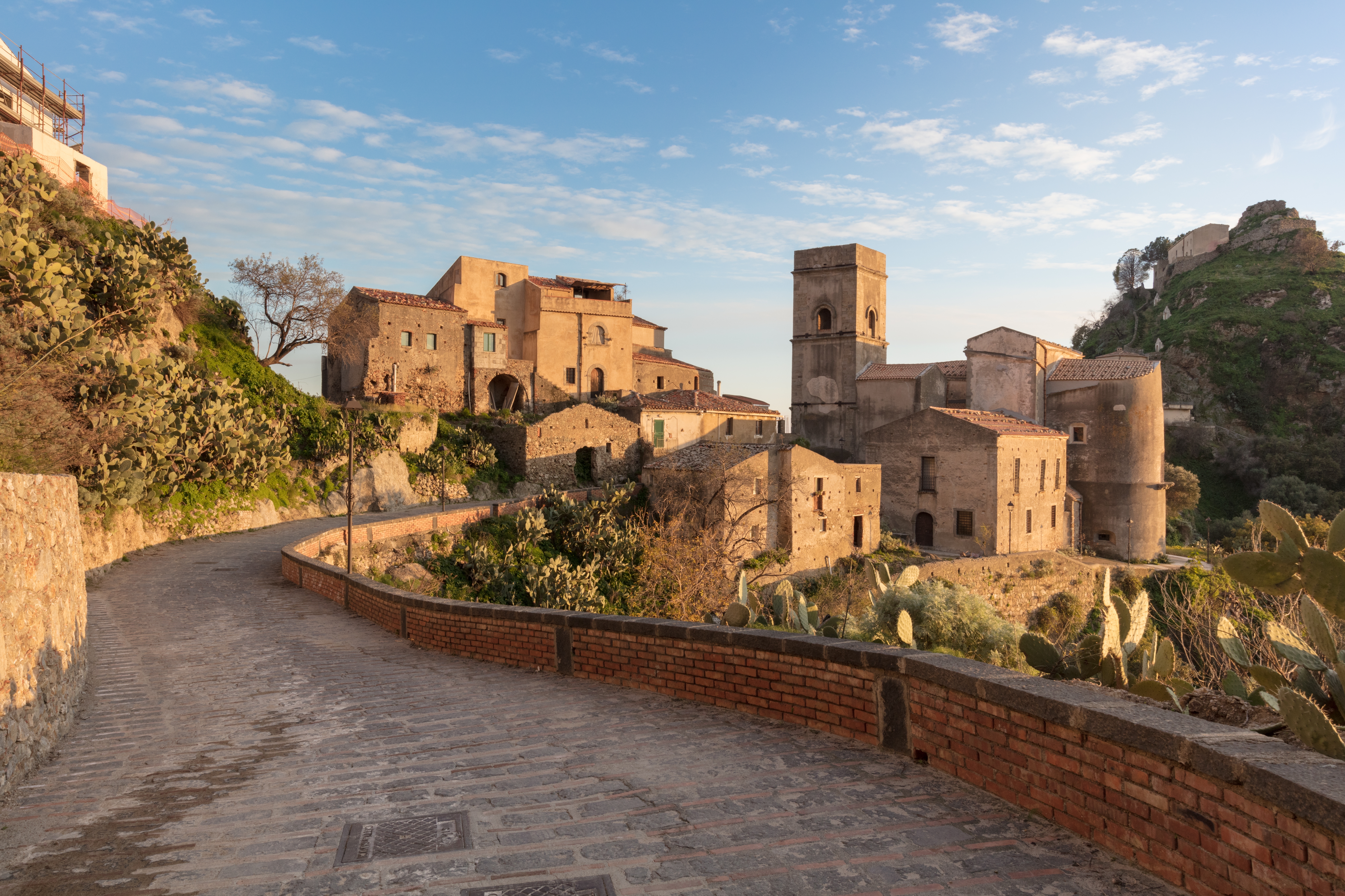 Historiske middelalderlige stenbygninger i Savoca på Sicilien ved solnedgang med brosten sti