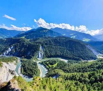Smuk schweizisk flod der snor sig gennem groen alpedal med bjerge