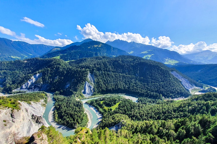 Smuk schweizisk flod der snor sig gennem groen alpedal med bjerge