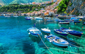 Farverige traditionelle fiskerbåde i den idylliske kystby Scilla i Calabrien med azurblåt Middelhav og charmerende huse langs kysten
